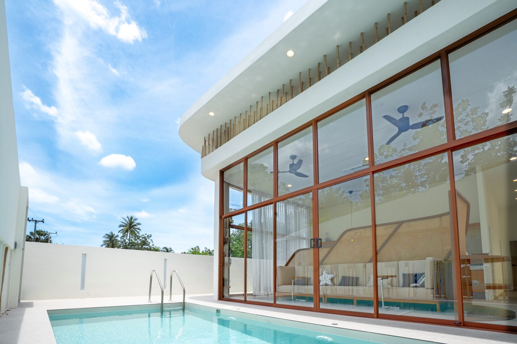 Curved white architecture and glass of a SandScape villa against a clear sky